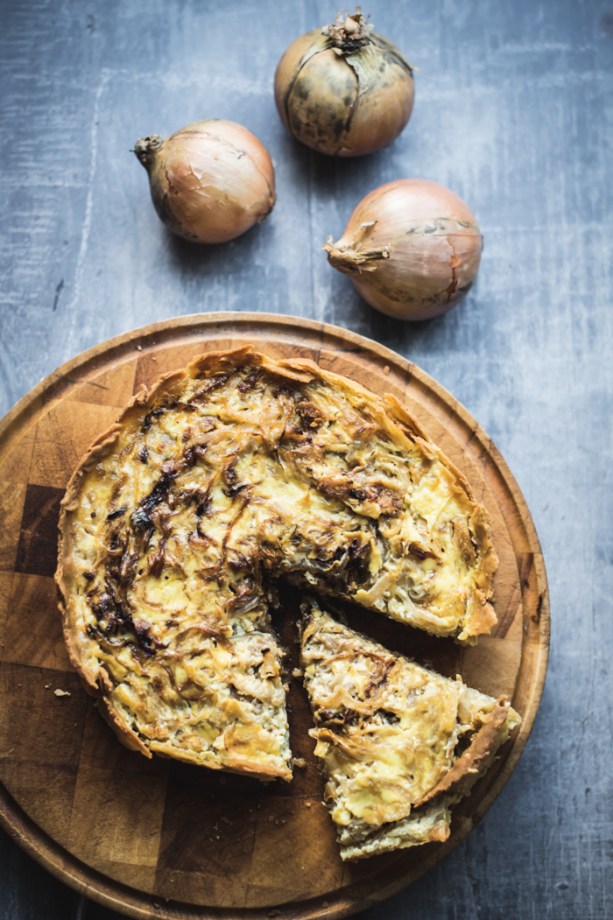 Onion tart and onions on a wooden board