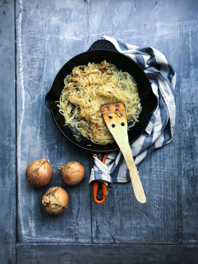 Caramelising onions in a frying pan for onion tart recipe