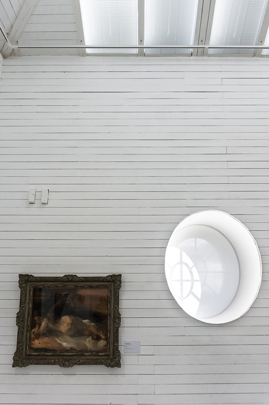 A painting on a wooden wall next to an oval window