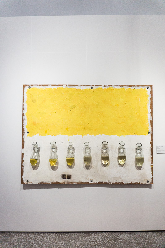 Painting of a yellow stripe with bottles below