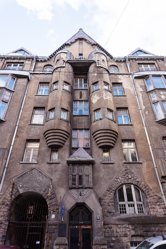 brown house with a pointed roof and barrel shaped columns in riga latvia