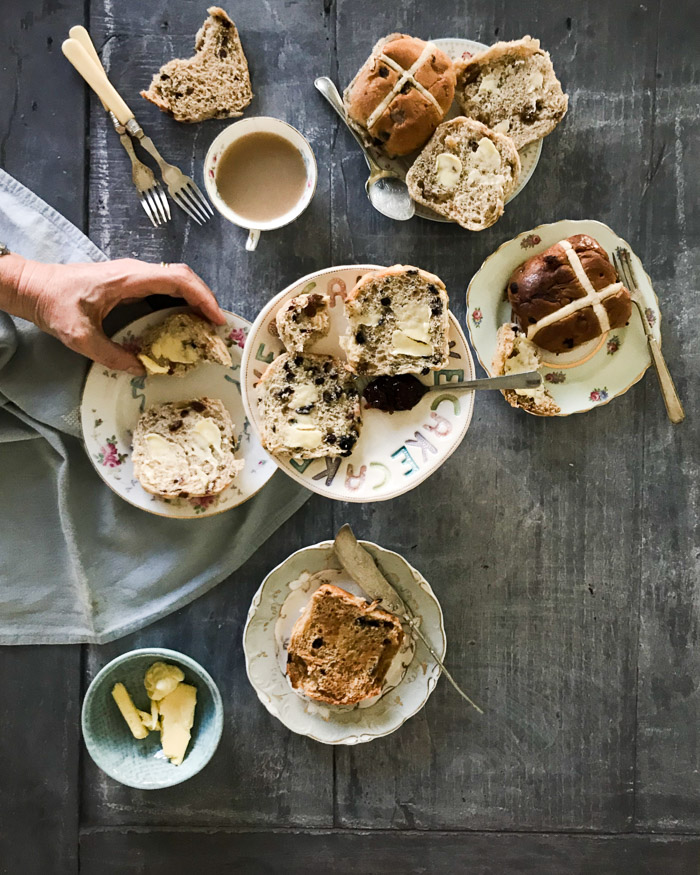 hot cross buns on plates with a cup of tea