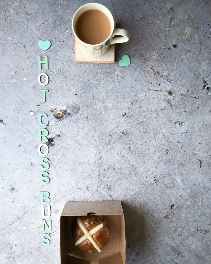 a cup of tea and a hot cross bun in a box