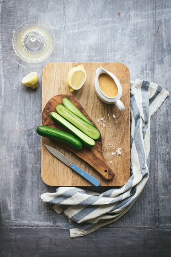 chopping board with jug of salad dressing and cucumbers