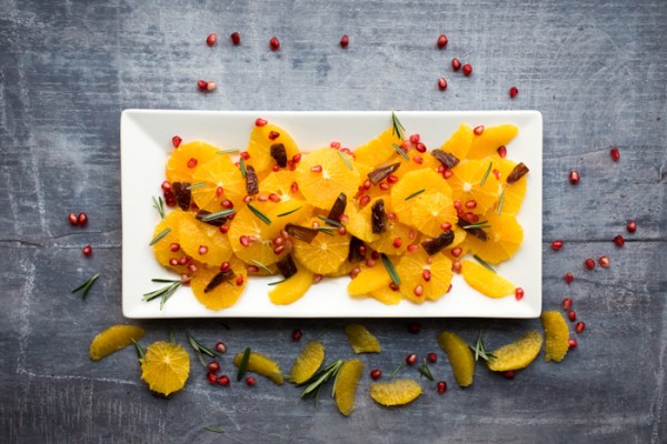 Date and orange fruit salad on a plate with segments scattered around