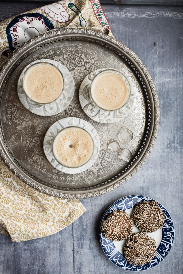 three glasses of lassi on a tray with a plate of biscuits