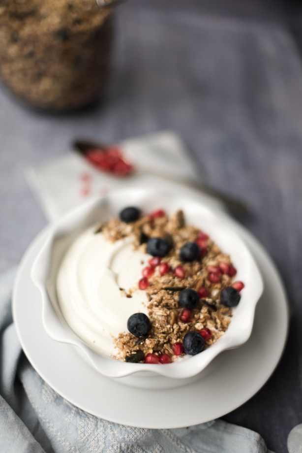 Bowl of granola over yoghurt with fruit and a spoon