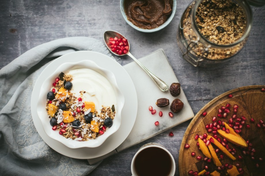 Bowl of granola over yoghurt with fruit and a spoon