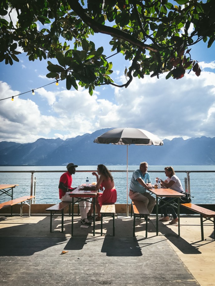 people sitting at tables by lake geneva