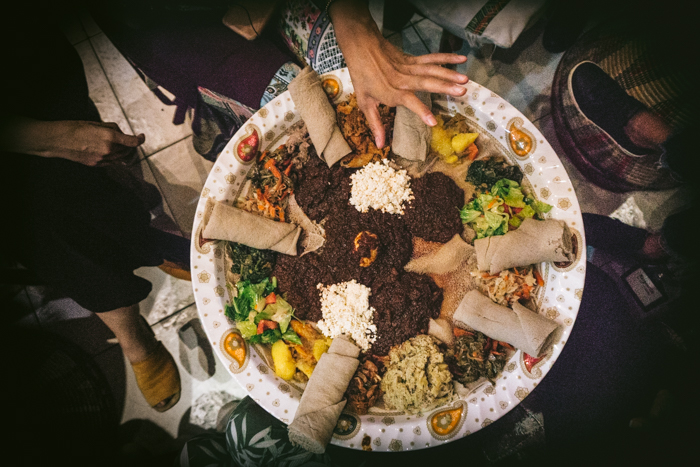 people eating a big platter of Ethiopian food with their hands