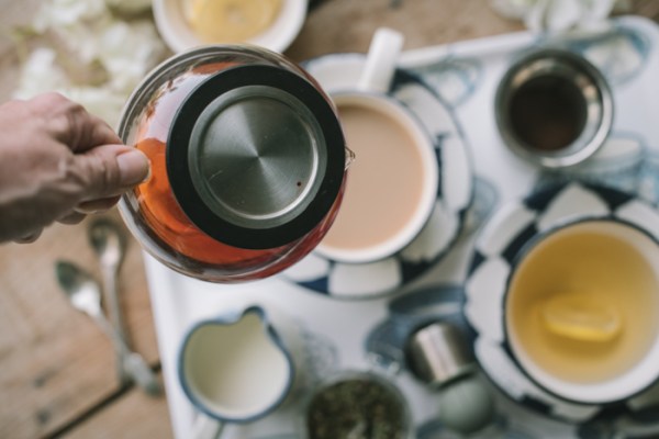 a teapot with loose tea pouring into a cup
