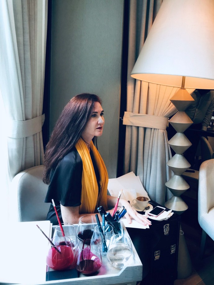 Hatty Pedder artist sitting in a chair beside her paints