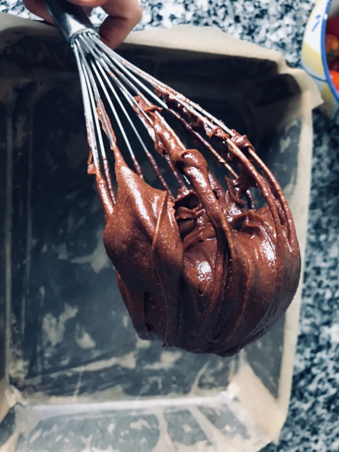 a whisk covered in chocolate brownie mixture