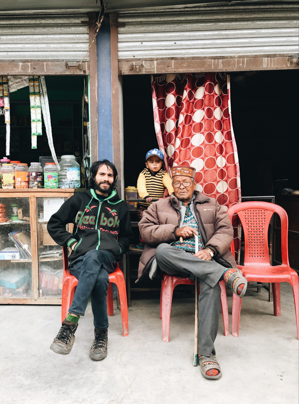 two men and a boy sitting on chairs in front of a shop