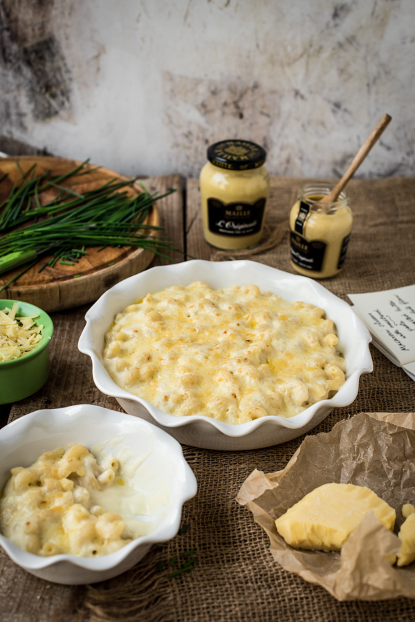 Two bowls of mustard macaroni cheese with two jars of Maille mustard