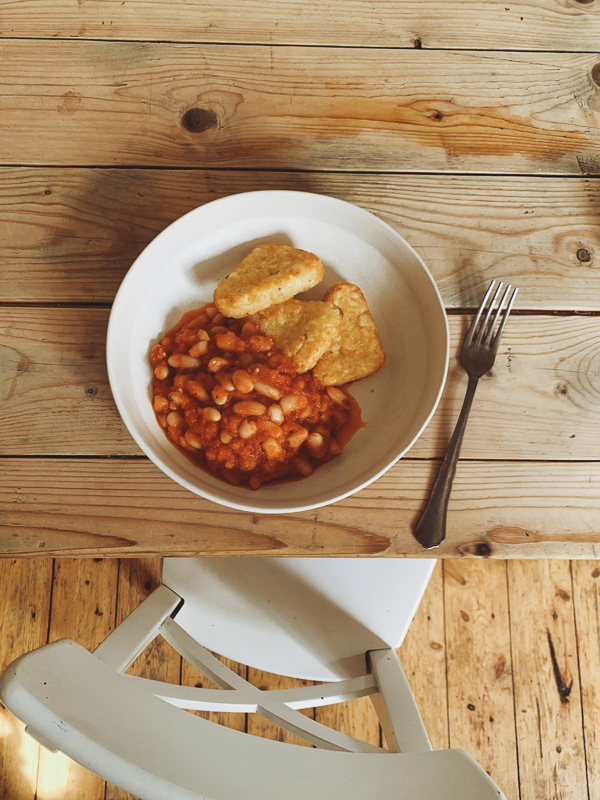 a bowl on hash browns and baked beans about to be eaten
