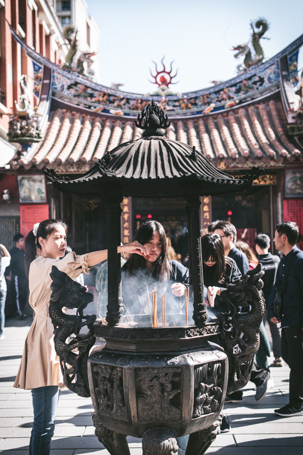 girls burning incense outside a temple