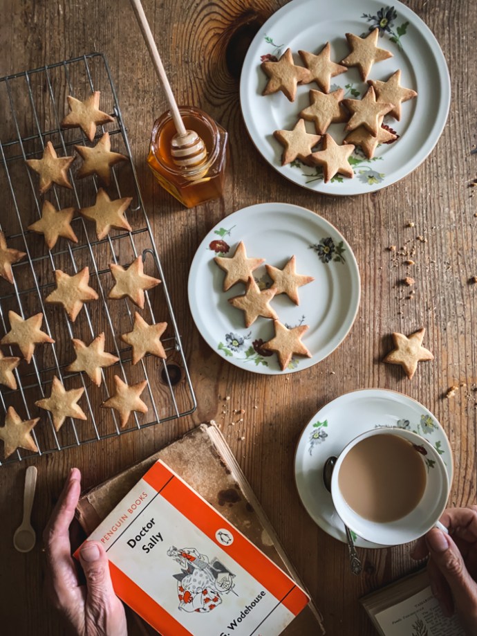 book, cup of tea and honey and ginger biscuits star-shaped
